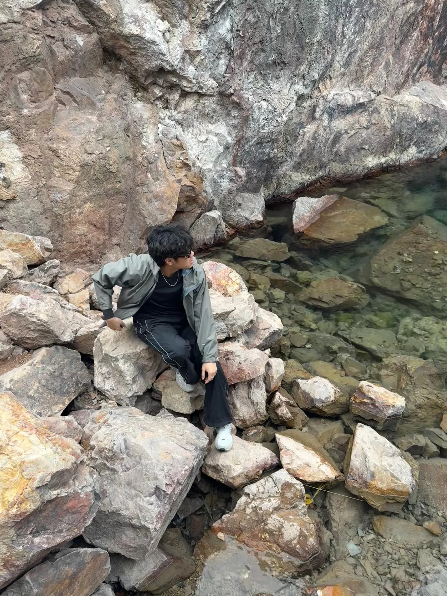 Ryder Xue seated on rocks beside the water